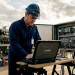Technician backing up PLC program on laptop